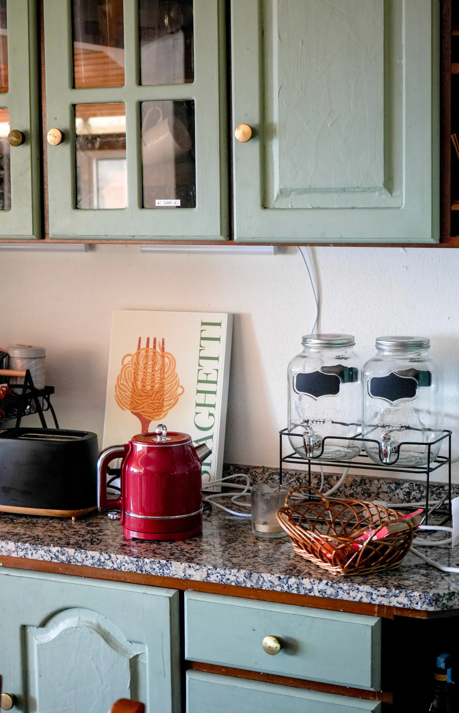 Shared kitchen with green cupboards and a red kettle on the worktop