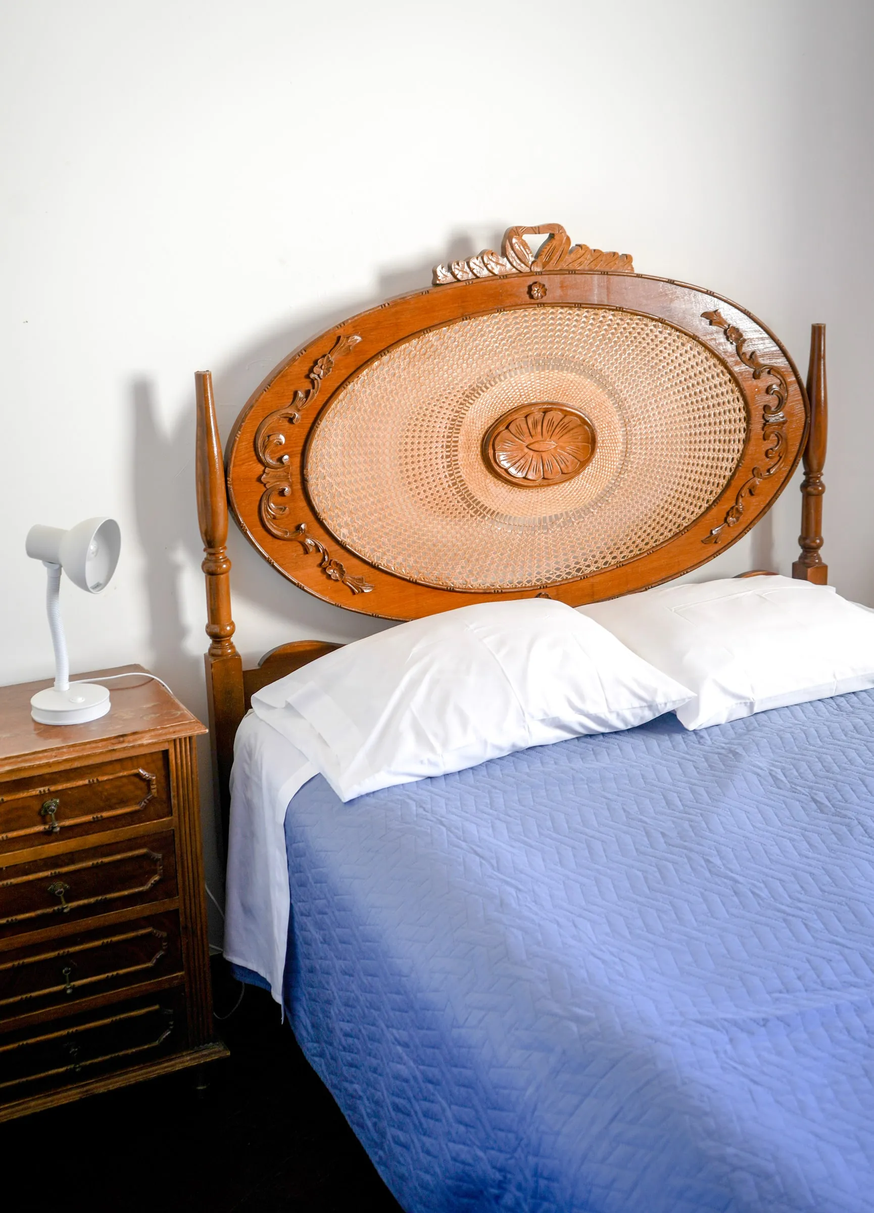 Linguine bed with a carved wooden headboard and blue cover