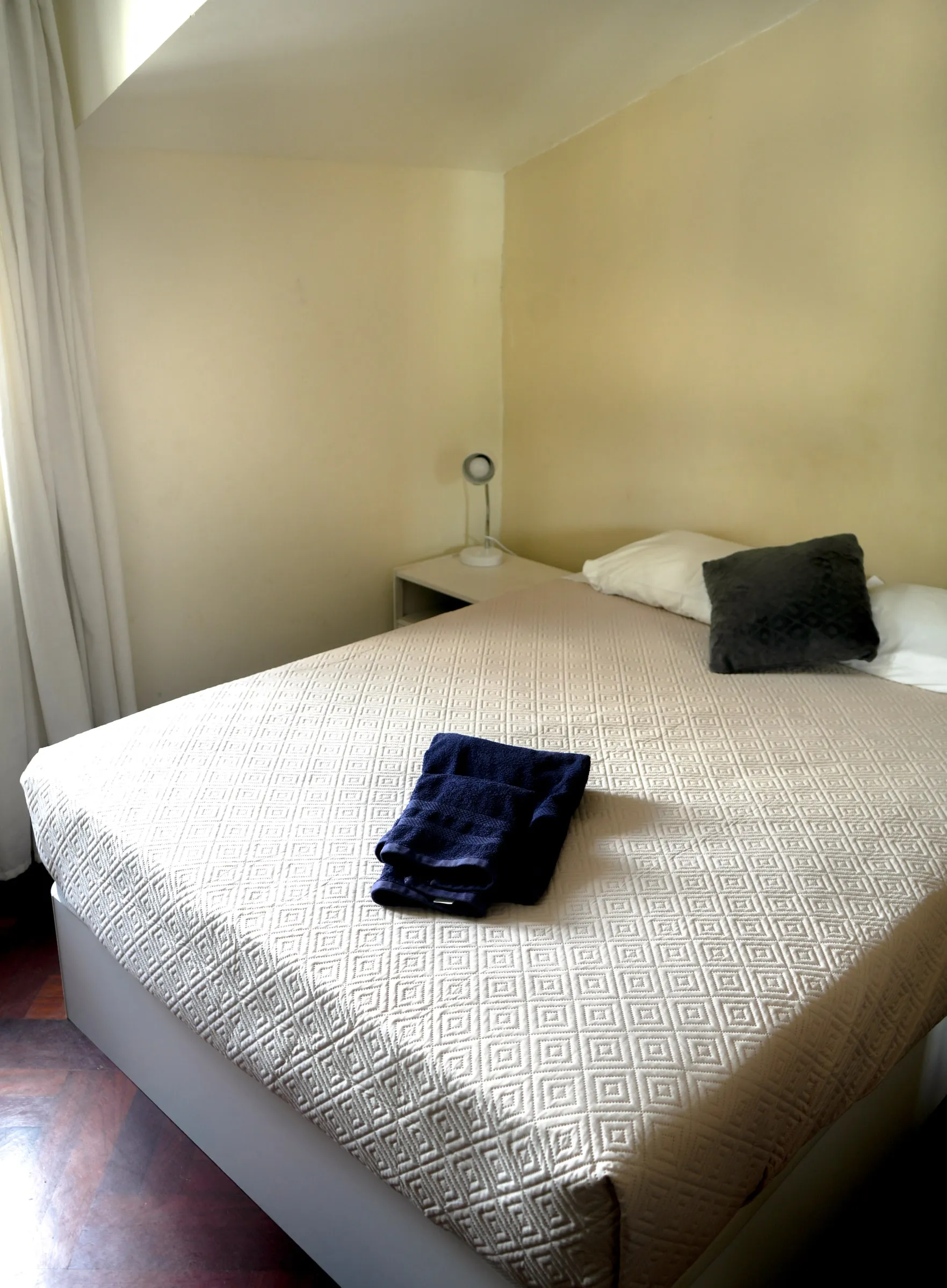 Orecchiette bed with folded towels and a grey cushion