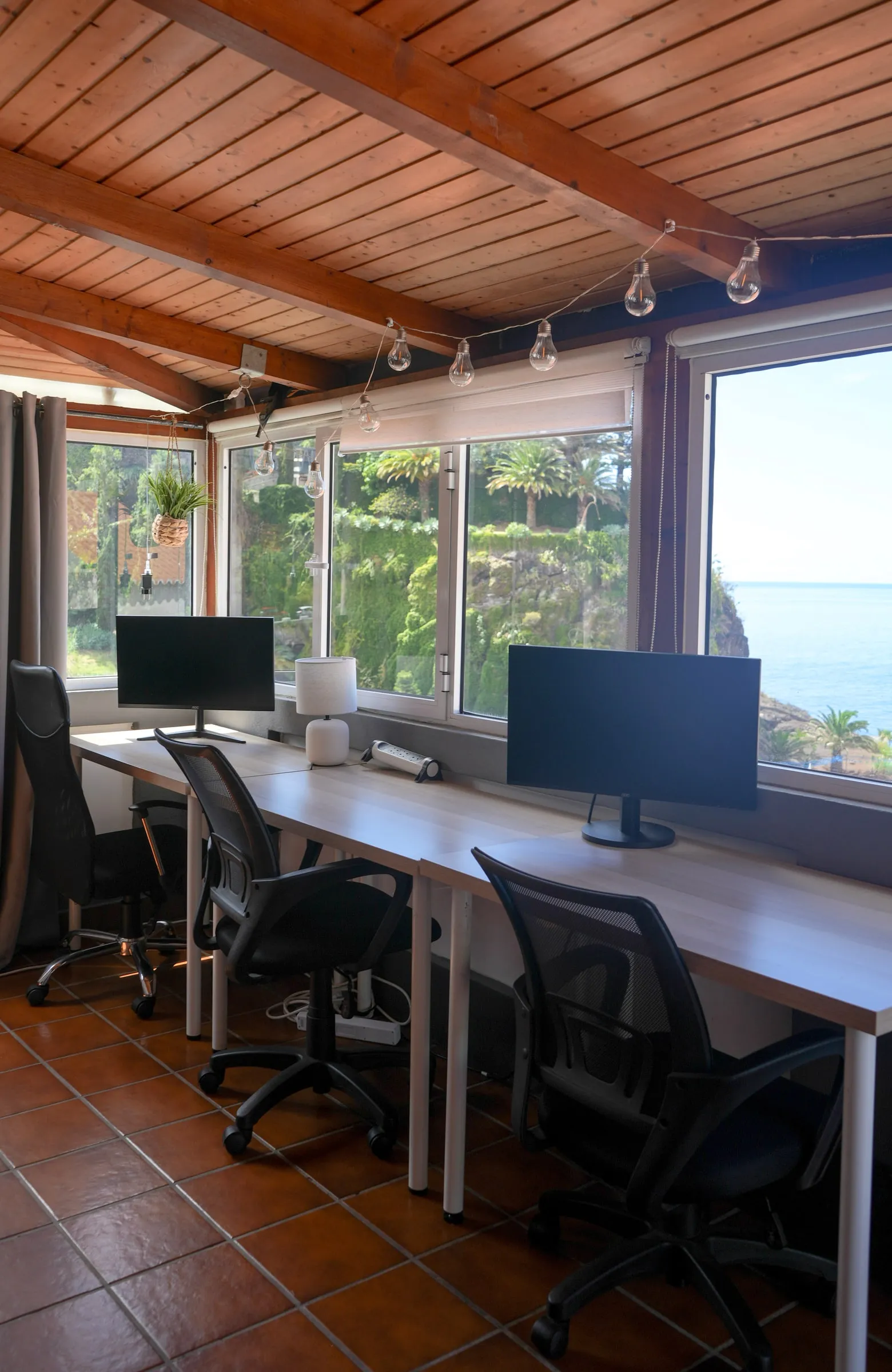 Shared desks, monitors and office chairs along the ocean-facing windows